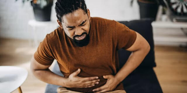 Middle-aged man experiencing mild digestive discomfort and bloating at home